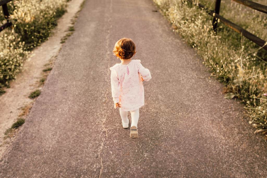 Bebê de vestido caminhando em estrada estreita em área de de campo