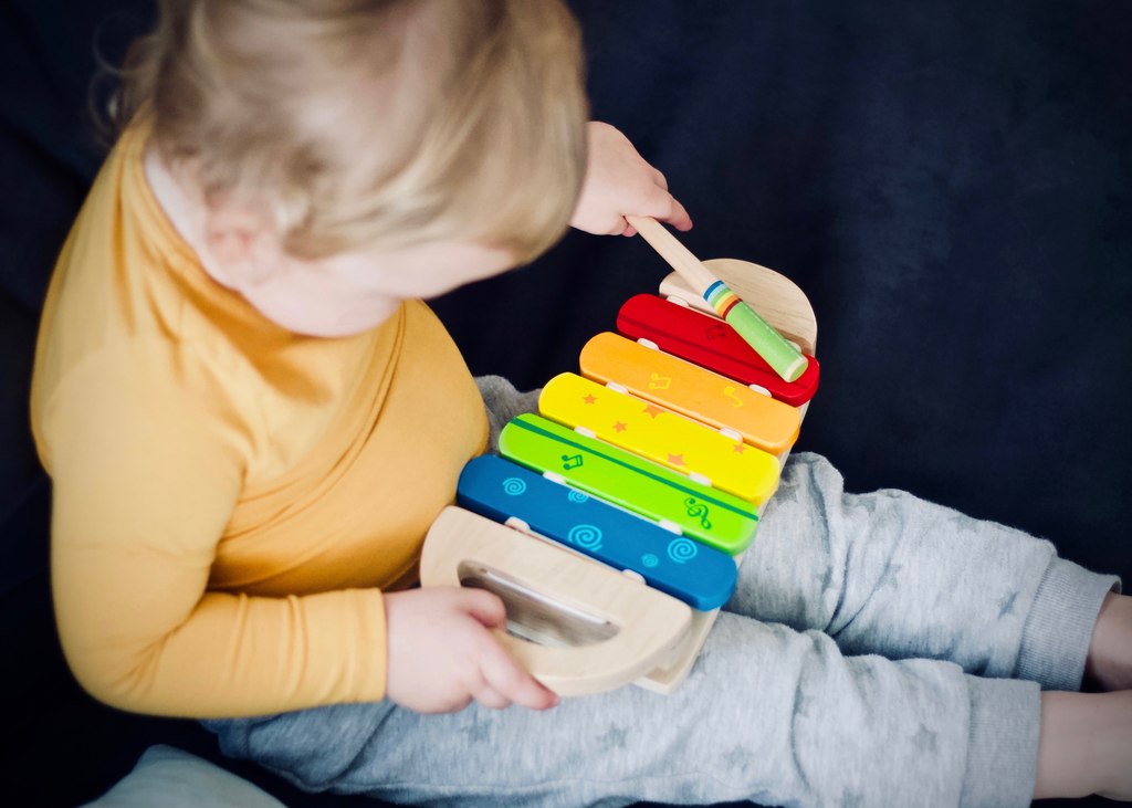 Criança brincando com xilofone colorido, simbolizando desenvolvimento das habilidades motoras finas